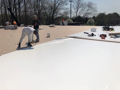 Technician spray-applying a protective roof coating on a commercial flat roof
